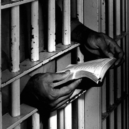 Inmate reading bible through prison bars